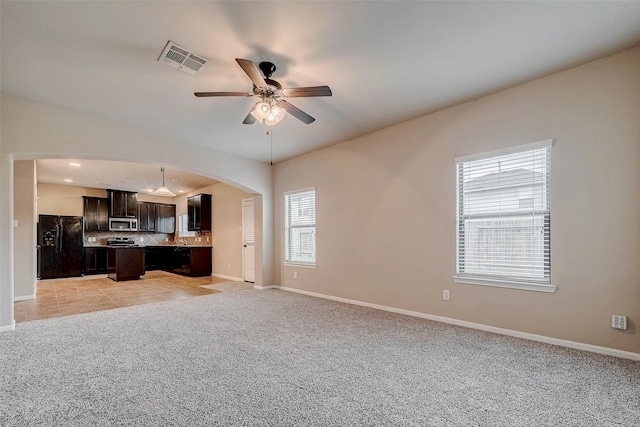 interior space featuring tasteful backsplash, visible vents, black fridge with ice dispenser, stainless steel microwave, and open floor plan