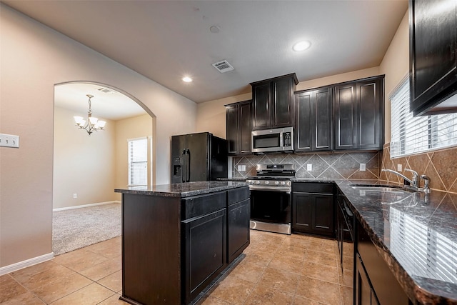 kitchen featuring tasteful backsplash, visible vents, appliances with stainless steel finishes, a center island, and a sink