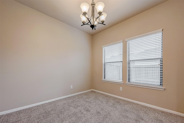 unfurnished room featuring an inviting chandelier, baseboards, and carpet flooring