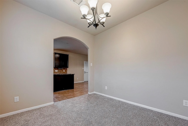 empty room with arched walkways, light colored carpet, visible vents, baseboards, and an inviting chandelier