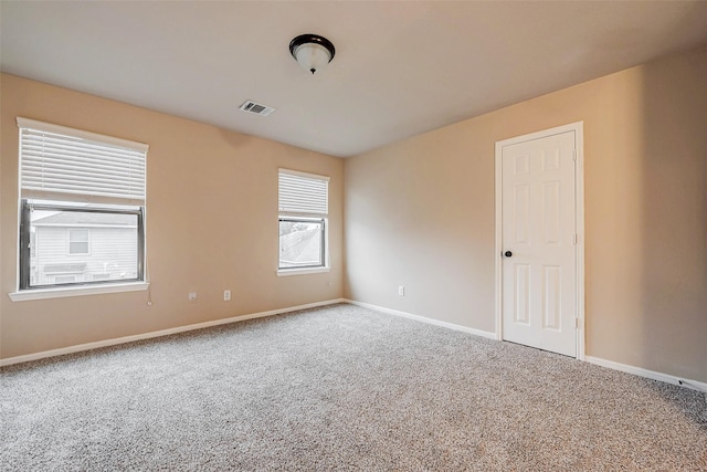 spare room with carpet flooring, visible vents, and baseboards