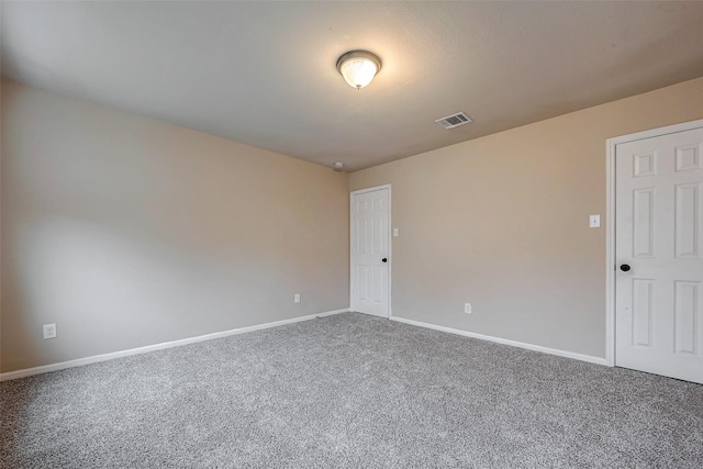 unfurnished room with carpet, visible vents, and baseboards