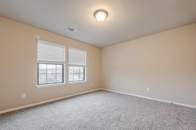 spare room with carpet, visible vents, and baseboards