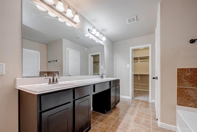 bathroom with double vanity, visible vents, tile patterned floors, a spacious closet, and a sink