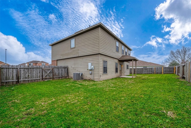 rear view of house with a fenced backyard, a yard, and central air condition unit