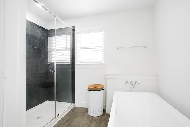 bathroom featuring a shower stall, a freestanding bath, baseboards, and wood finished floors