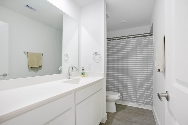 bathroom with curtained shower, visible vents, toilet, vanity, and wood finished floors