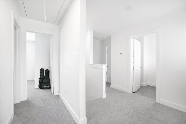 corridor featuring attic access, carpet, an upstairs landing, and baseboards