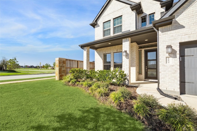 doorway to property featuring brick siding and a yard