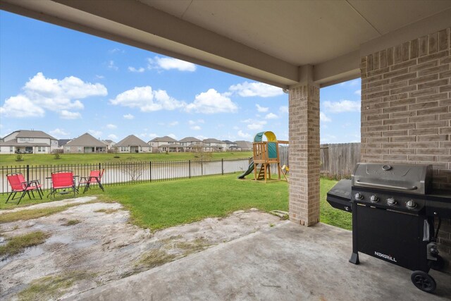 view of patio featuring a playground, a water view, area for grilling, a residential view, and a fenced backyard