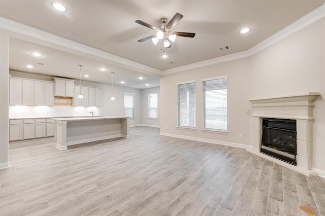 unfurnished living room with baseboards, visible vents, crown molding, and light wood finished floors