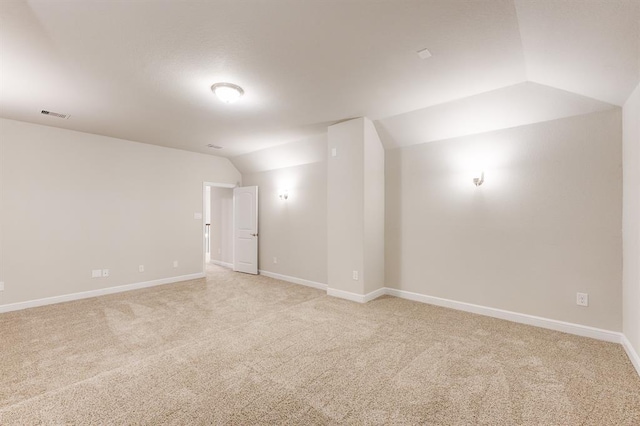 unfurnished room with lofted ceiling, light carpet, visible vents, and baseboards