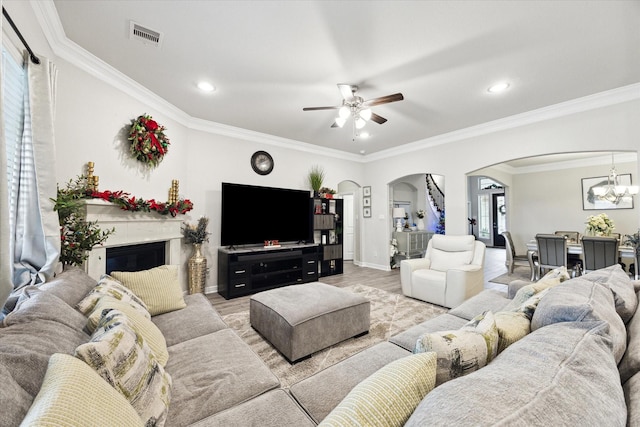 living room featuring visible vents, arched walkways, baseboards, light wood-style flooring, and ornamental molding