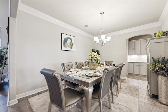 dining area with visible vents, baseboards, light wood-style floors, ornamental molding, and an inviting chandelier