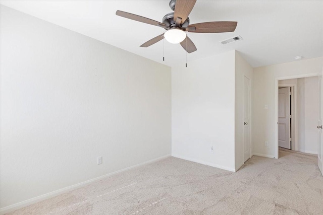 carpeted spare room with baseboards, visible vents, and a ceiling fan