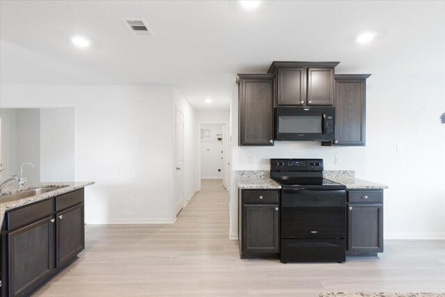 kitchen featuring visible vents, light wood-style flooring, dark brown cabinets, black appliances, and a sink