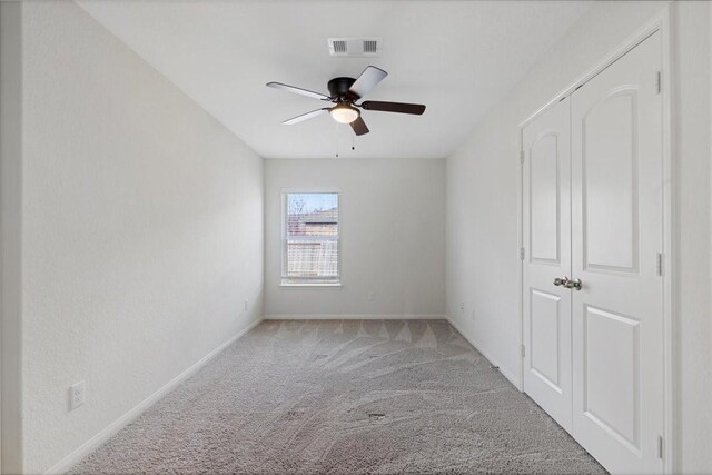 unfurnished room with light carpet, baseboards, visible vents, and a ceiling fan