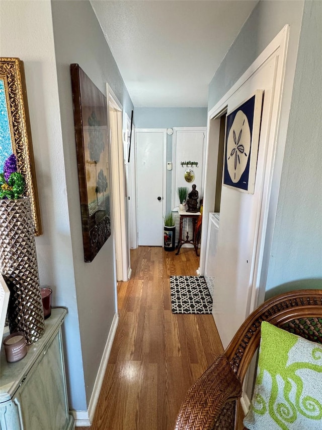 corridor featuring baseboards and wood finished floors