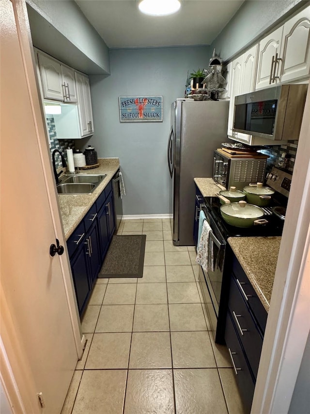 kitchen featuring light tile patterned flooring, a sink, white cabinets, light countertops, and appliances with stainless steel finishes