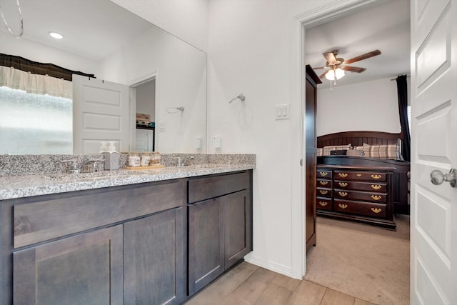 bathroom with ceiling fan, baseboards, wood finished floors, and vanity