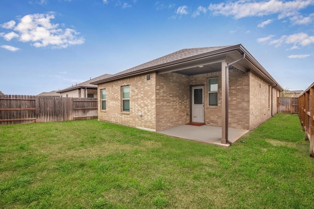 rear view of property with a patio area, brick siding, a yard, and a fenced backyard