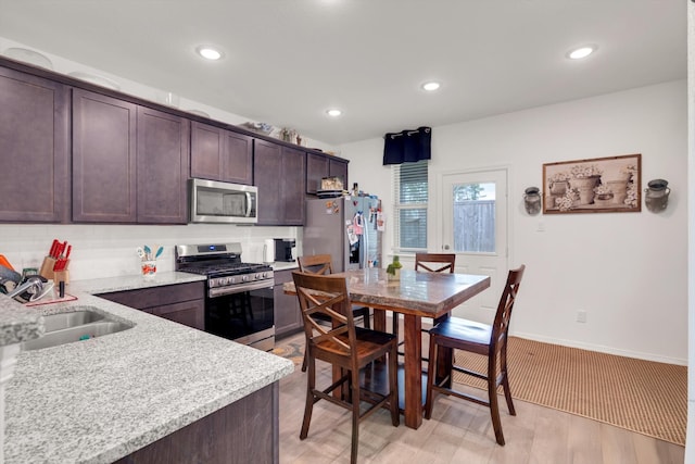 kitchen with dark brown cabinets, appliances with stainless steel finishes, a sink, and recessed lighting