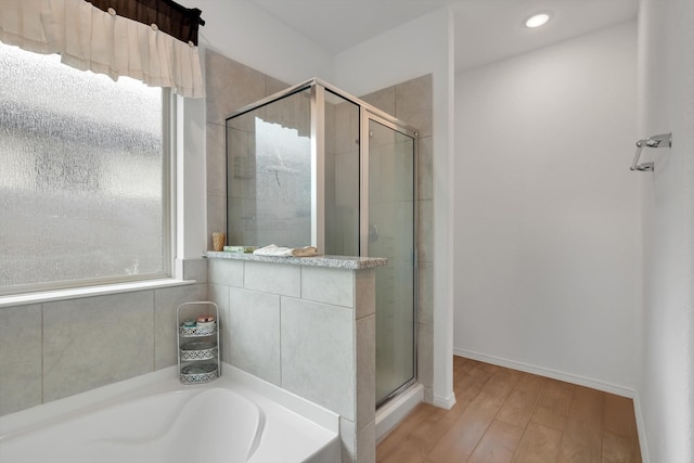 bathroom with recessed lighting, wood finished floors, baseboards, a shower stall, and a bath