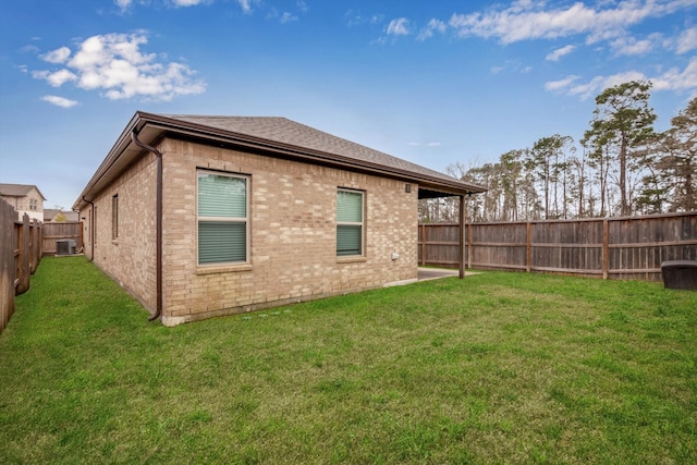 back of property featuring a fenced backyard, cooling unit, a lawn, and brick siding