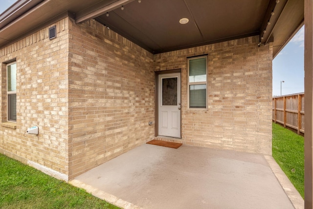 entrance to property with brick siding and fence