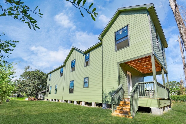 rear view of property featuring a deck and a lawn