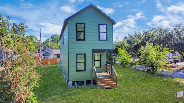 rear view of house with a lawn and fence