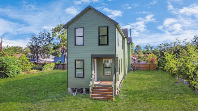 rear view of property with a yard and fence