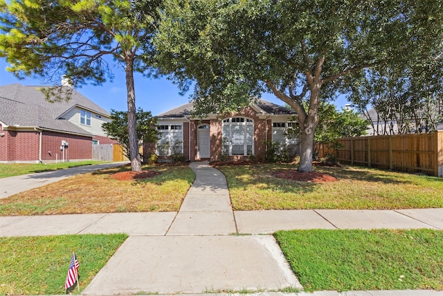 view of front of property with brick siding, fence, and a front yard