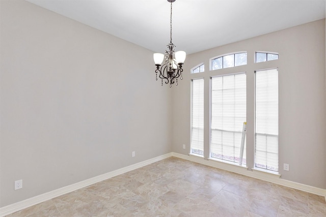 unfurnished room with a chandelier and baseboards