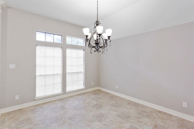 empty room featuring a notable chandelier and baseboards