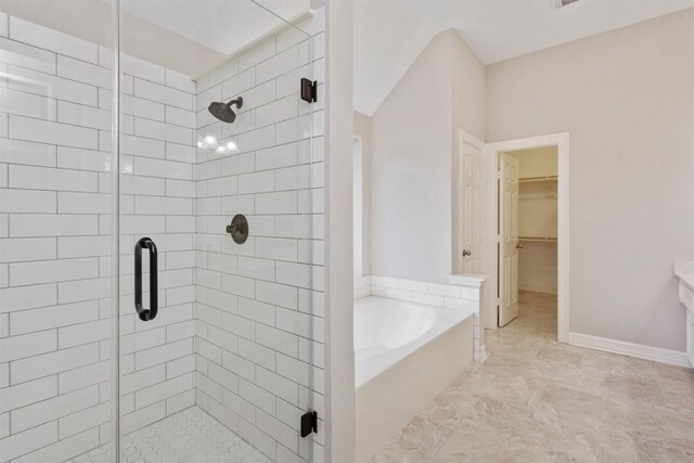 bathroom featuring a garden tub, a spacious closet, and a shower stall