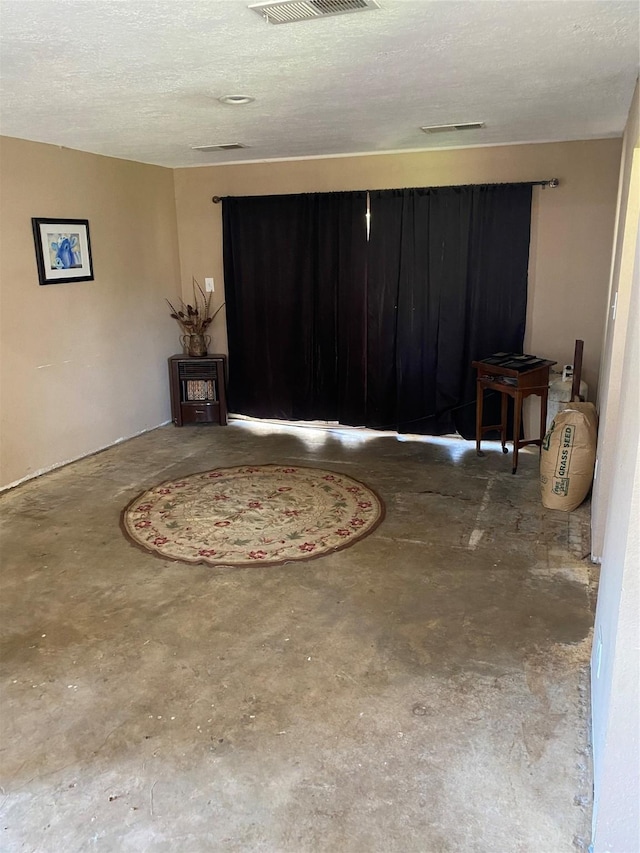 interior space featuring a textured ceiling, visible vents, and unfinished concrete flooring