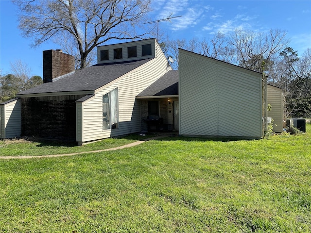 exterior space with roof with shingles, a lawn, a chimney, and central AC unit