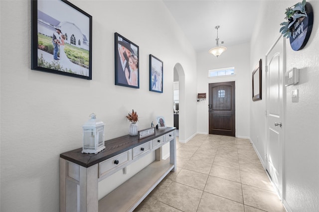 entryway with light tile patterned floors, baseboards, and arched walkways