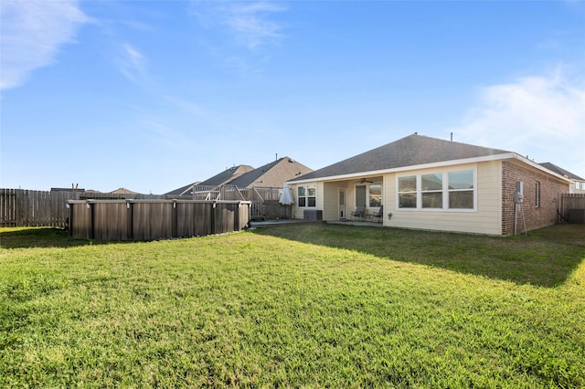 rear view of property with brick siding, a lawn, and a fenced backyard