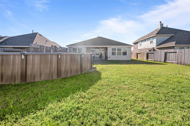 back of house featuring a fenced backyard and a lawn