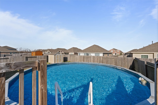 view of swimming pool featuring a fenced backyard, a residential view, a storage unit, and a fenced in pool