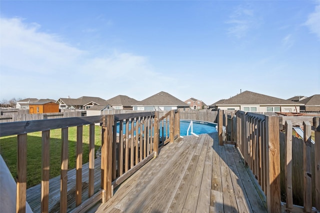 wooden deck featuring a fenced in pool, a residential view, a fenced backyard, and a lawn