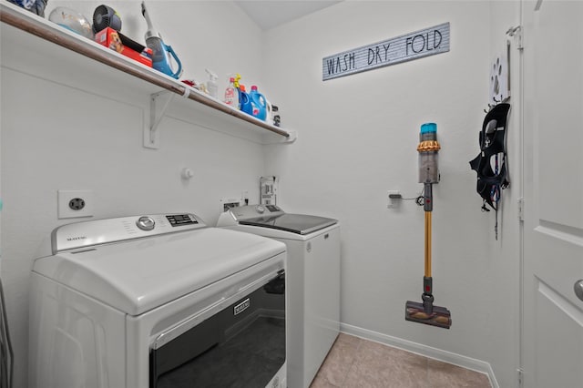 clothes washing area with baseboards, laundry area, light tile patterned floors, and washer and dryer