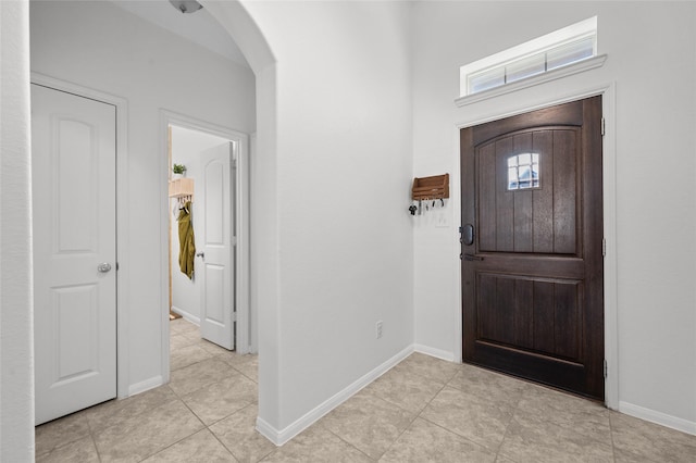 entrance foyer with arched walkways, light tile patterned flooring, and baseboards