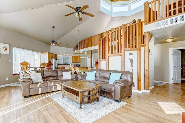 living room with baseboards, high vaulted ceiling, a ceiling fan, and light wood-style floors