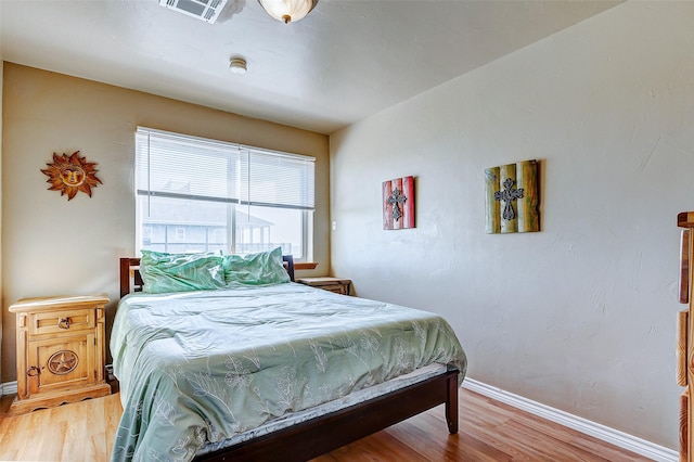 bedroom with light wood-type flooring, baseboards, and visible vents