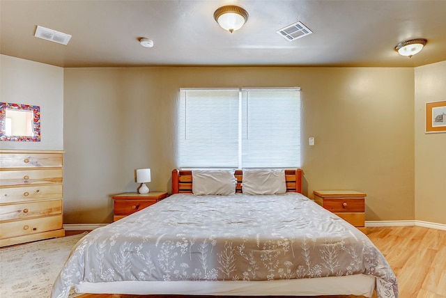 bedroom featuring baseboards, visible vents, and wood finished floors