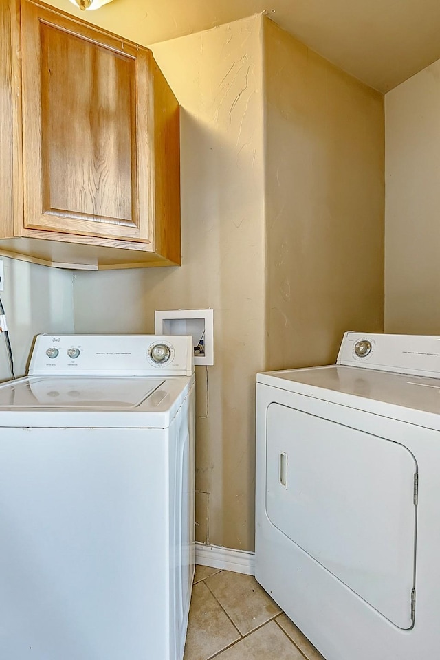 washroom with light tile patterned floors, cabinet space, and washer and dryer