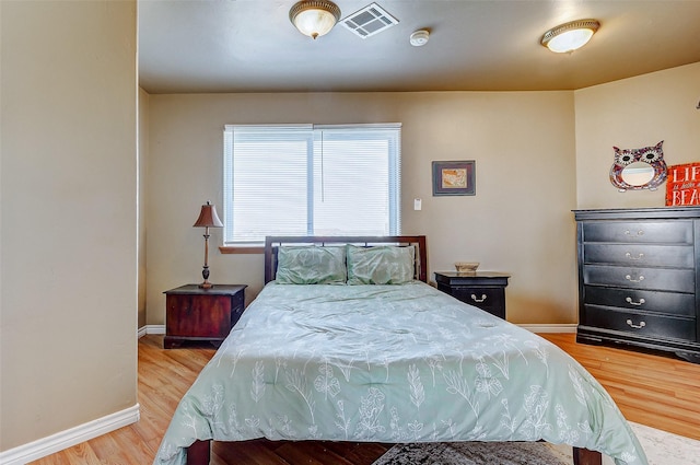 bedroom featuring visible vents, light wood-style flooring, and baseboards